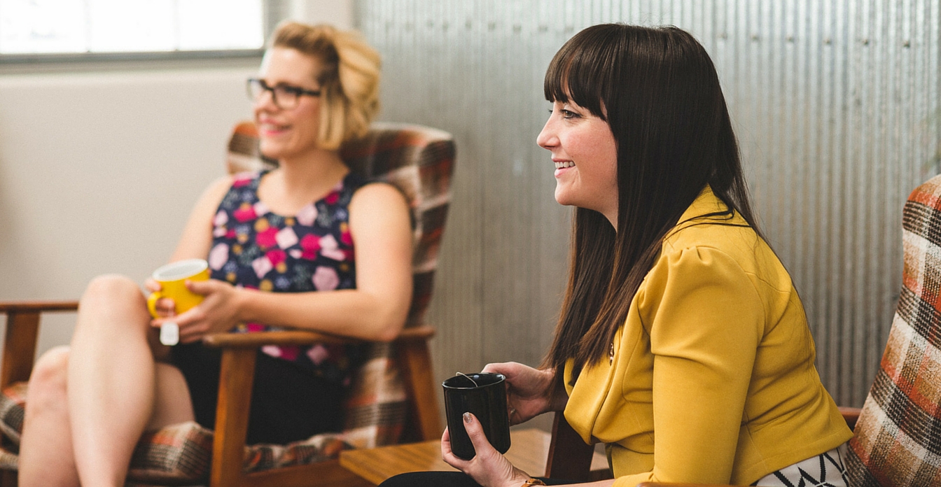 Two women drinking tea and laughing.